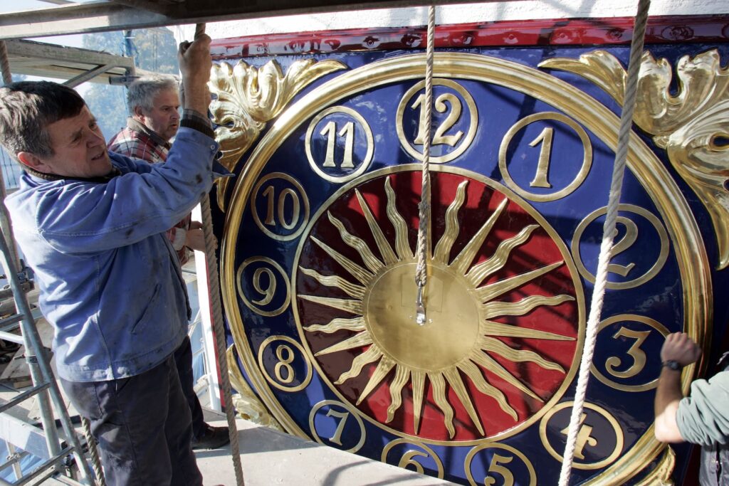 Montage des renovierten Zifferblattes am Thurn und Taxis Gebäude in der Regensburger Waffnergasse